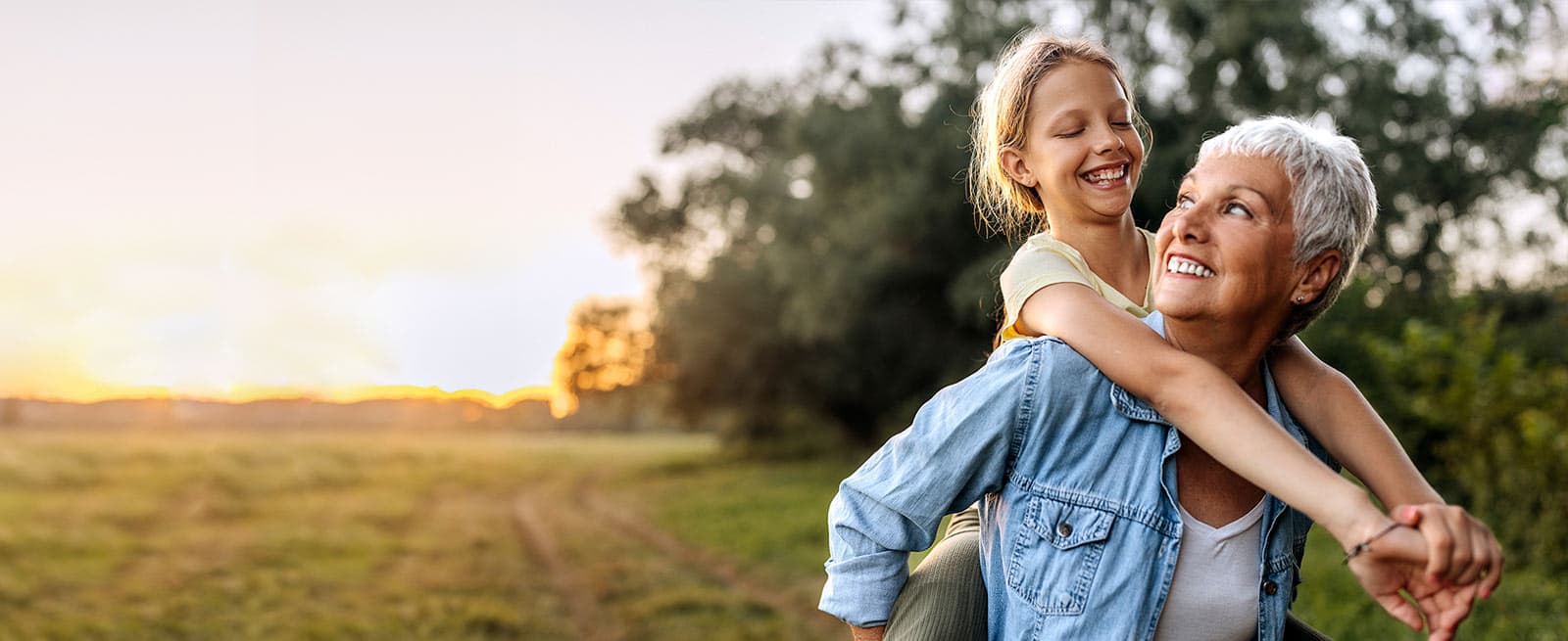 Grandmother carrying her granddaughter on back outdoors