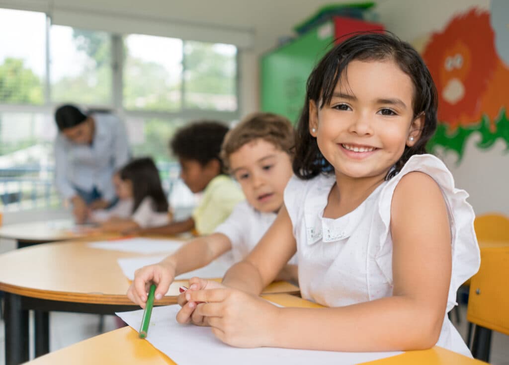 Portrait of a happy Latin American girl at the school looking at the camera smiling - education concepts