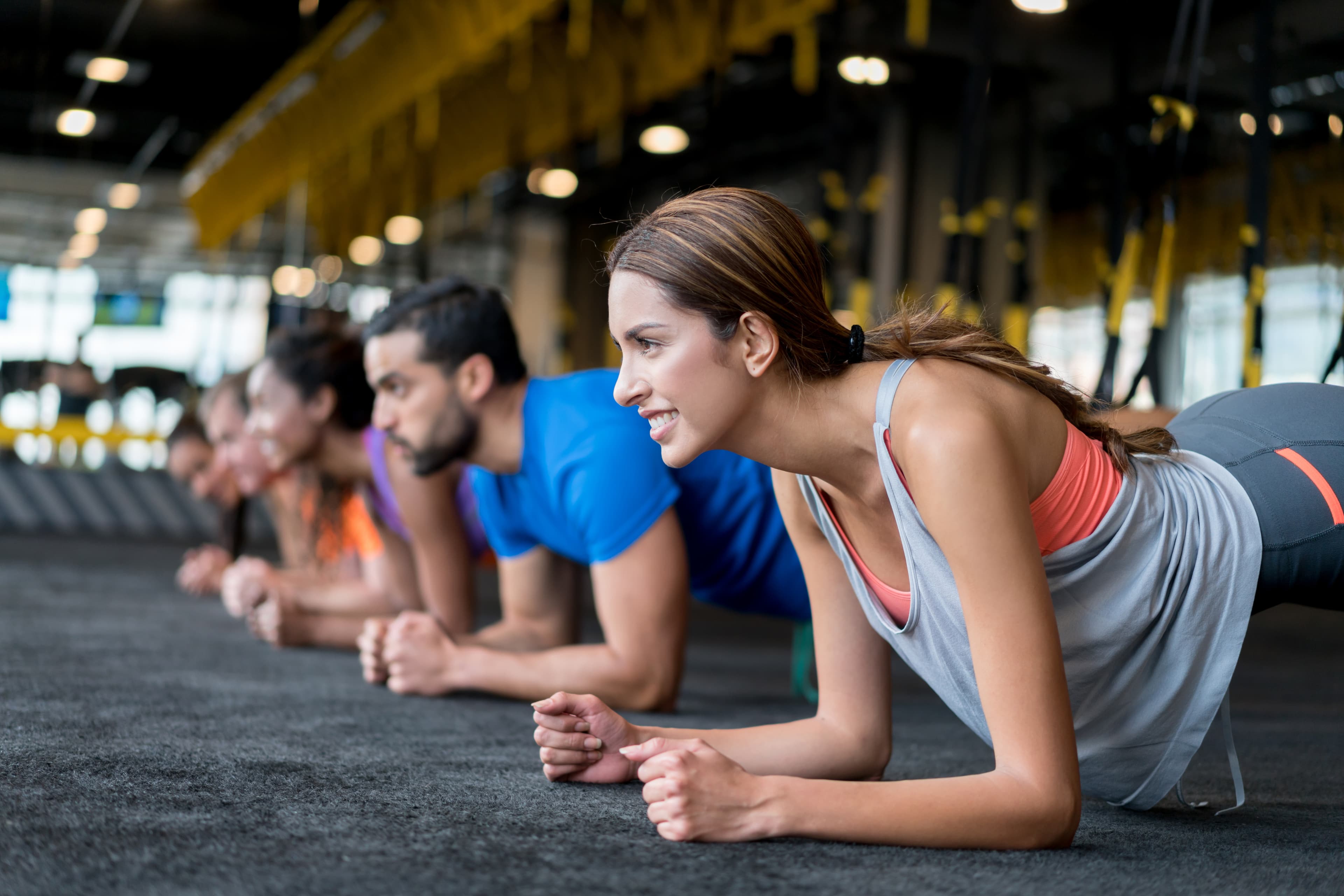 Group of people exercising at the gym in a suspension training class â fitness concepts