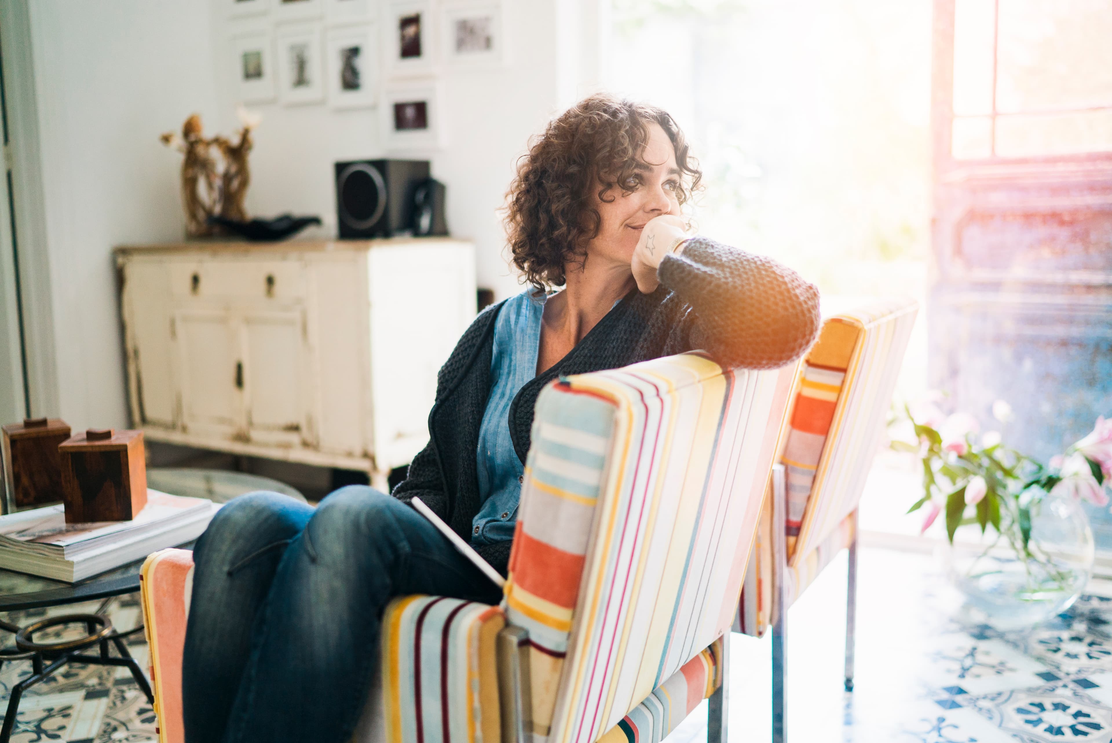 Pensive woman sitting at home, with hand on chin.