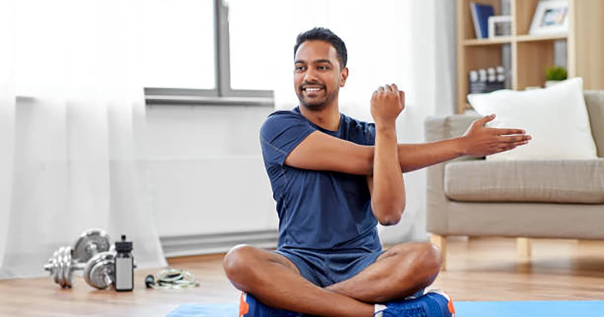 sport, fitness and healthy lifestyle concept - indian man training and stretching arm at home