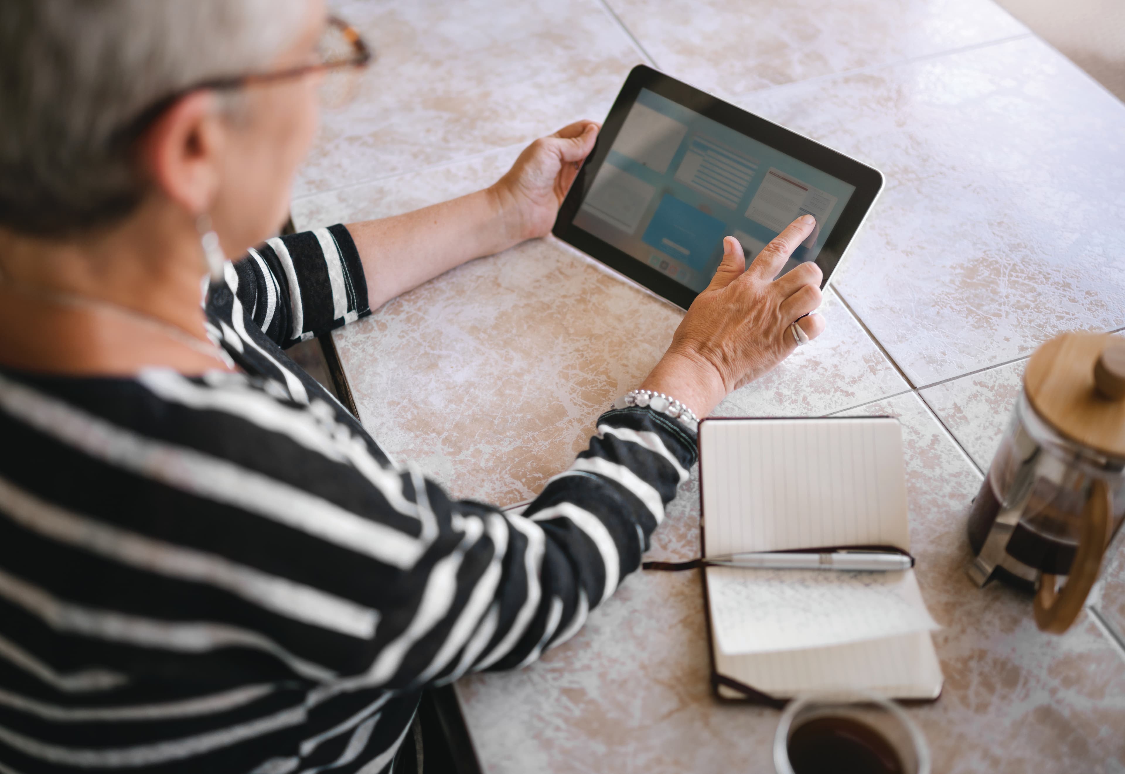 Top view of mature woman making notes interacting on a digital tablet