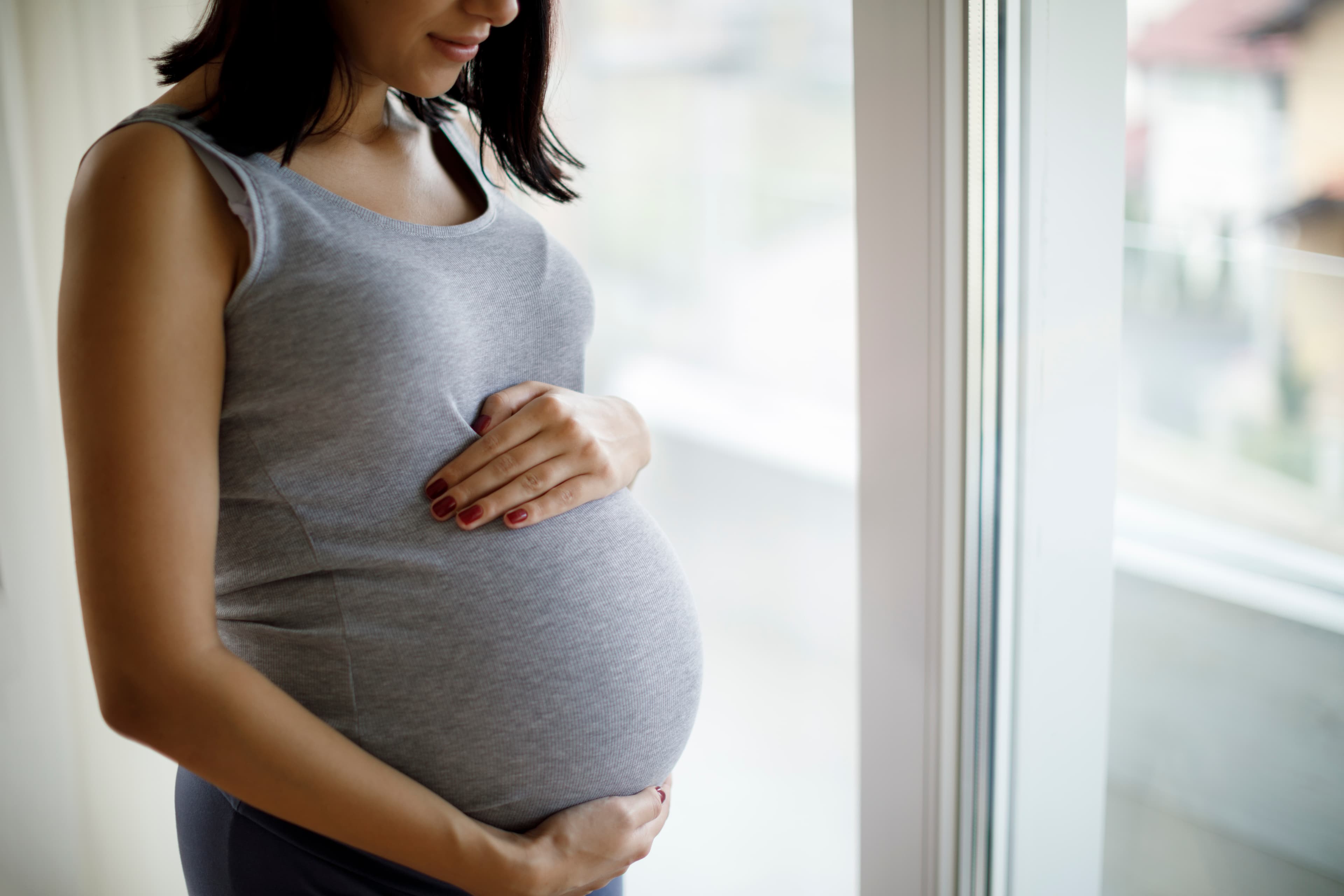 Pregnant woman holding belly cropped