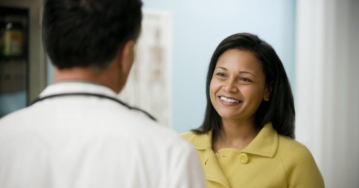 A woman smiles at a doctor